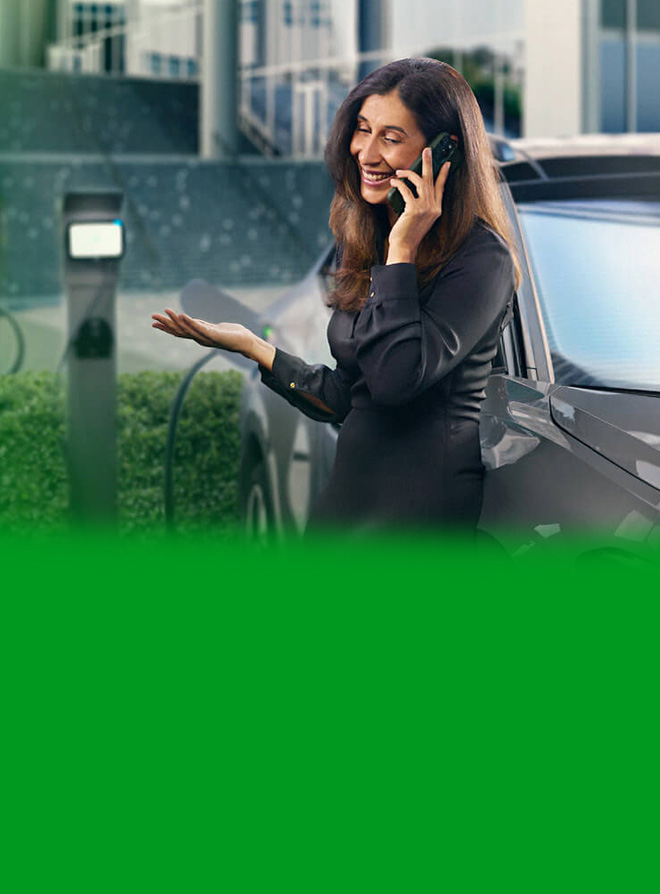 Ejecutiva junto a un vehículo eléctrico cargando en una empresa